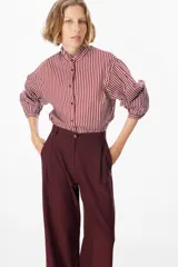 Camisa de manga larga con estampado de rayas verticales en color bordó y blanco. Presenta un cuello alto con volados y cierre frontal con botones a tono.