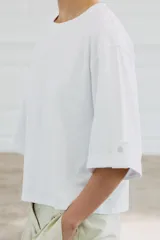 Camiseta de algodón con cuello redondo, manga tres cuartos con detalle de botón metálico y bajo recto.