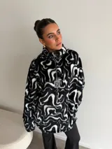Buzo de peluche con estampado animal print, cuello alto con cierre frontal parcial y detalle de etiqueta decorativa en el pecho.