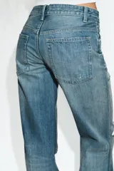 Jeans de tiro medio con diseño flare, efecto lavado y detalles de roturas en las piernas. Presenta cinco bolsillos, trabillas para cinturón y bajo deshilachado sin costuras.