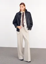 Blazer color beige con solapas de muesca, cierre frontal de dos botones oscuros, bolsillos con solapa en los laterales y un bolsillo ojal en el pecho.