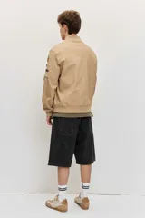 Campera bomber de gabardina color tostado, con cierre frontal y bolsillos laterales, puños y cintura elastizados de rib.