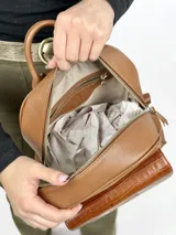 Mochila grande de cuero marrón con bolsillo frontal con textura de cocodrilo y cierre superior con cremallera.