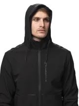 Campera softshell negra con capucha ajustable, cierre frontal completo y bolsillos laterales con cierre. Presenta puños con ajuste de velcro y logo de la marca estampado en el pecho.