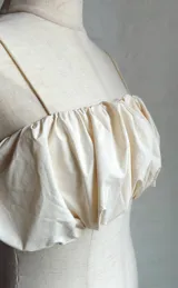 Top corto color crema con breteles finos y fruncido en el busto.