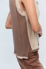 Chaleco de punto color beige con escote en V y ribete blanco.