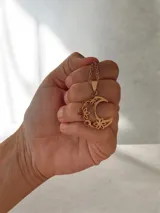 Collar de cadena fina con dije de luna creciente decorada con estrellas pequeñas, en acero quirúrgico dorado.