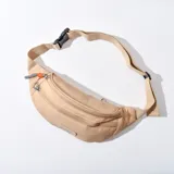 Riñonera color beige con tres compartimentos con cierre y correa ajustable con hebilla.