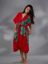 Capullo o kimono de paño 100% algodón, color rojo con estampado exclusivo en tono verde, de morfología amplia y envolvente, con bolsillos laterales y cinto independiente para ajustar la cintura.