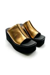 Sandalias de cuero vacuno color dorado, con plataforma corrida negra y punta cuadrada.