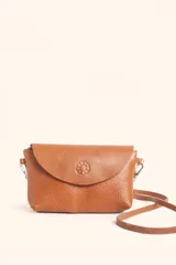 Cartera tipo sobre de cuero color marrón, con solapa frontal redondeada que presenta un detalle circular grabado. Incluye correa larga ajustable y extraíble, cierre principal y broche de seguridad.