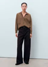 Cardigan de punto fino color marrón, con cuello en pico, cierre frontal de botones y dos bolsillos de parche delanteros. Presenta un diseño recto de manga larga con cuello tipo polo en un tono más oscuro.