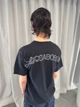Remera de algodón color negro con estampado serigráfico en tono gris oscuro en la parte posterior. Presenta cuello reforzado, costuras reforzadas y una pequeña etiqueta decorativa en la manga.
