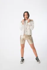 Campera de jean color crudo con cuello alto y apliques de galones dorados y plateados en cuello y hombros.