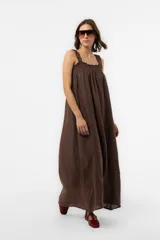 Vestido largo de lino color marrón, de silueta amplia y caída liviana, con escote cuadrado fruncido y tirantes anchos con volados.