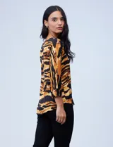Blusa de gasa satén estampada con diseño animal print en tonos naranja y negro, de la marca Ninety. Tiene mangas tres cuartos y cuello redondo.