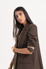 Blazer sastrero de corte oversize y diseño recto, color marrón chocolate. Presenta solapas clásicas, hombreras estructuradas, cierre frontal de un botón y bolsillos laterales con tapa.