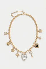 Collar de cadena de eslabones dorados con múltiples dijes colgantes, incluyendo estrellas, un corazón central grande de cristal transparente, una llave, flores y un corazón esmaltado en negro.