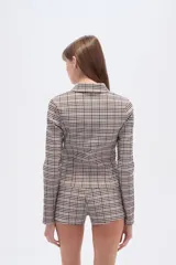 Camisa de viscosa a cuadros en tonos beige, marrón y blanco, con cuello camisero, cierre frontal y corte ajustado al cuerpo.