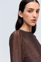 Remera plateada de lurex con escote redondo, calce al cuerpo y mangas largas estilo princesa.