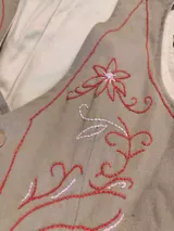 Chaleco sastrero de acrocel de algodón color beige, con escote en V, cierre frontal con botones y bolsillos ribeteados con detalles a contratono.