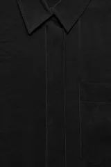 Camisa de corte fluido confeccionada en mezcla de modal, con cuello solapa, manga corta con dobladillo y bolsillo de plastrón en el delantero. Presenta cierre frontal con botones ocultos por tapeta y aberturas laterales en el bajo.