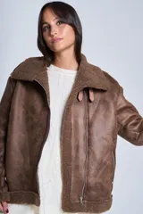 Campera gamulán marrón de símil cuero, con interior de corderoy al tono, cierre frontal con cremallera y cuello con solapas grandes. Presenta detalles de hebillas en los puños y bolsillos laterales con cierre.