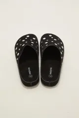 Suecos tipo zueco color negro con acabado de gamuza, decorados con tachas metálicas plateadas circulares. Poseen suela plana y diseño abierto en el talón.