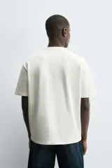 Camiseta de manga corta y cuello redondo, color blanco roto, con textura seersucker.