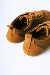 Championes de estilo urbano confeccionados en una combinación de cuero texturizado y gamuza en tonos marrones, con suela plana y diseño minimalista.