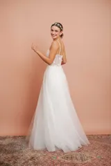 Vestido largo blanco de alta costura, con corset estructurado de tirantes finos con apliques florales y falda amplia de tul con brillo.