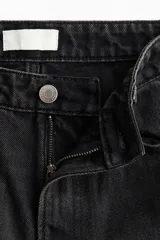 Jean wide leg de tiro alto en denim de algodón negro, con diseño de cinco bolsillos, perneras amplias y cierre frontal con botón y cremallera.