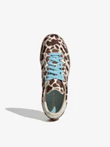 Championes Adidas Samba OG con diseño de estampado animal print de vaca en tonos marrón y blanco. Presenta las icónicas tres bandas laterales en blanco, cordones en color celeste y suela de goma natural.