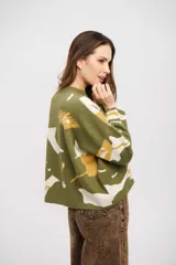 Buzo de tejido de punto con diseño estampado abstracto en tonos verde, blanco y mostaza. Presenta cuello redondo, mangas largas y un corte holgado con ruedo recto.