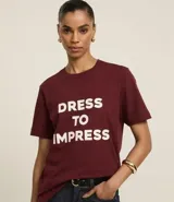 Remera color borgoña de algodón, con cuello redondo y mangas cortas. Estampa frontal con la frase "Dress to Impress" en letras mayúsculas blancas.