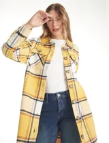 Sobrecamisa larga de tejido soft con diseño de cuadros en tonos amarillos, blancos y negros. Presenta cuello con solapa, cierre frontal con botones, mangas largas con puños abotonados y bolsillos aplicados en el frente.