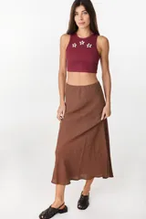 Musculosa de algodón en color bordó, de corte corto, con cuello redondo y detalles de flores decorativas aplicadas en el pecho.