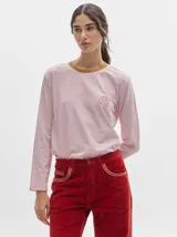 Pantalón de pana roja con corte holgado y tiro medio. Presenta una línea dorada a lo largo de la pierna.