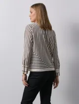 Blusa de gasa estampada con líneas verticales negras sobre fondo beige, de manga larga con puño abotonado. Espalda con abertura y botón.