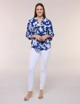 Blusa de gasa de calce suelto y caída ligera, color azul con estampado floral blanco. Presenta escote en V con cuello mao, tabla central, mangas largas regulables con presilla y botón, ruedo redondeado de estilo mullet y espalda con canesú y pliegue central.