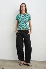 Pantalón estilo cargo color negro, confeccionado en tela avión, con cintura elastizada ajustable mediante cordón y puños regulables en los tobillos con tiras para ajustar.