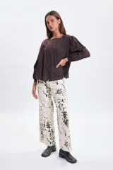 Pantalon de jean de corte ancho y tiro medio, color crudo con estampado de manchas irregulares en tonos oscuros. Presenta un diseño de pierna recta y ruedo desflecado.