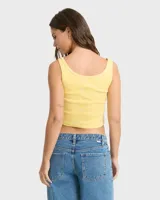 Top musculosa Billabong de corte crop en color amarillo, con diseño estampado frontal de flor tropical y texto en tonos rosados y naranjas.