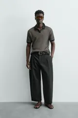 Polo de manga corta con cuello solapa y cierre frontal de dos botones. Tejido de punto con textura de rombos en tonos negro y beige, con ribetes negros en cuello, mangas y bajo.