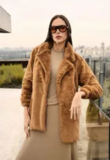 Campera de piel sintética en color tostado, con solapas amplias, mangas largas y corte recto. Su diseño de textura suave y envolvente ofrece un acabado elegante y cálido.