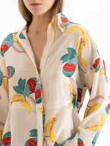 Camisa de seda color beige con estampado colorido de frutas, cuello camisero, mangas largas y ajuste elástico en la cintura.