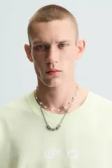 Camiseta de corte relaxed fit, color verde lima pálido, con cuello redondo y manga corta. Presenta un estampado sutil en el pecho.