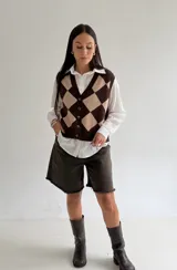 Chaleco tejido de punto con diseño de rombos en tonos marrón y beige, con escote en V y cierre frontal de botones.