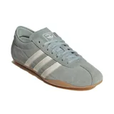 Championes Adidas Tokyo de perfil bajo, confeccionados en gamuza color verde con detalles en blanco y suela de goma marrón. Presentan las clásicas tres tiras laterales y la inscripción 'adidas TOKYO' estampada en dorado.