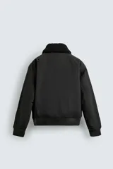 Cazadora bomber de corte cropped confeccionada en algodón, color negro. Presenta cuello de solapa con efecto borreguillo a contraste, cierre frontal con cremallera metálica, bolsillos delanteros tipo plastrón con solapa y acabados en rib en puños y bajo.